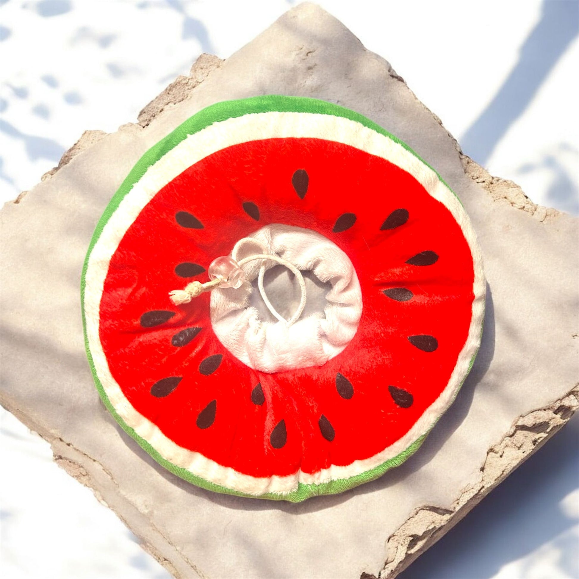 Pet medical collar  shaped like a watermelon slice on a textured surface