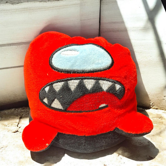 Red plush toy with a smiling face on a wooden surface