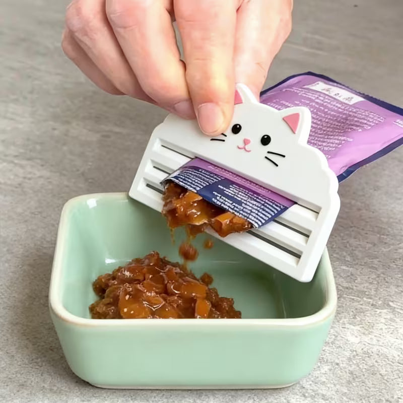 Cat food packaging being opened with a cat-shaped tool over a green container.