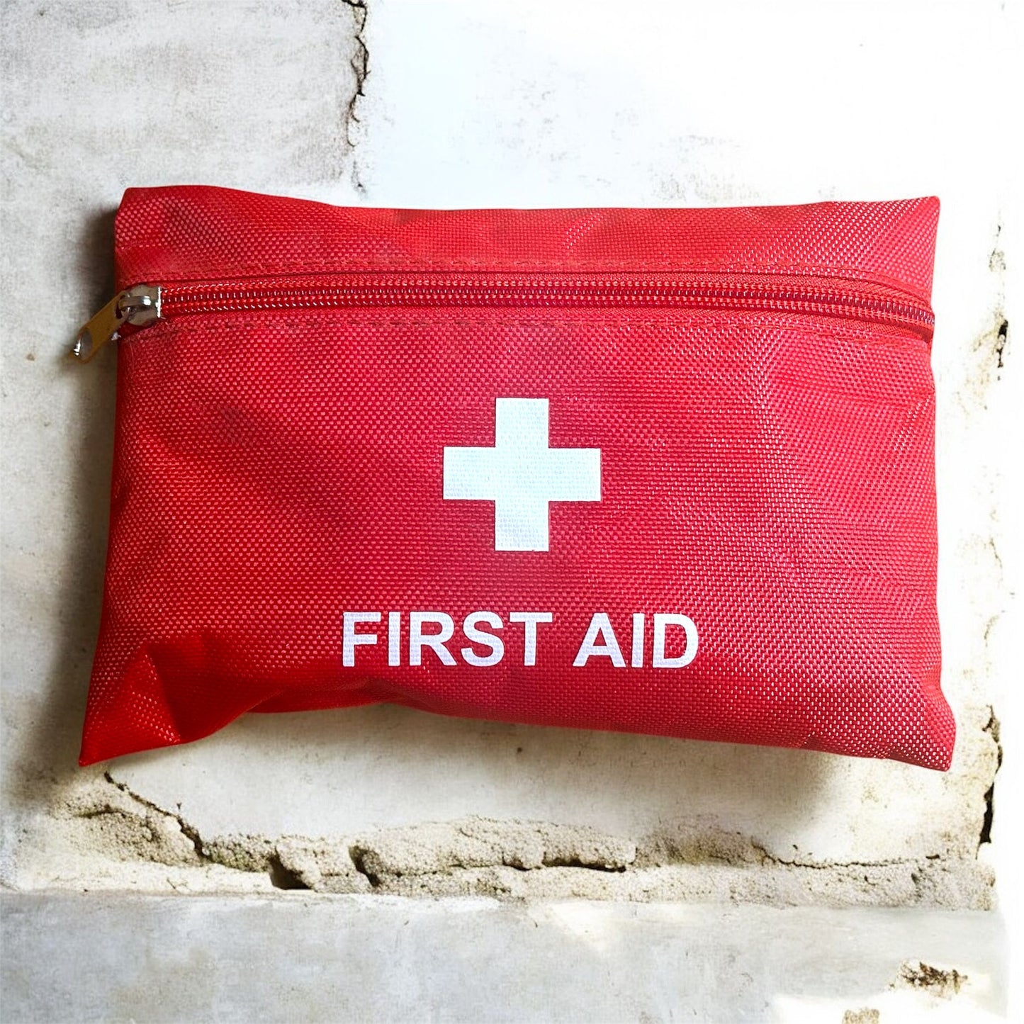 Red first aid kit with a white cross on a textured surface
