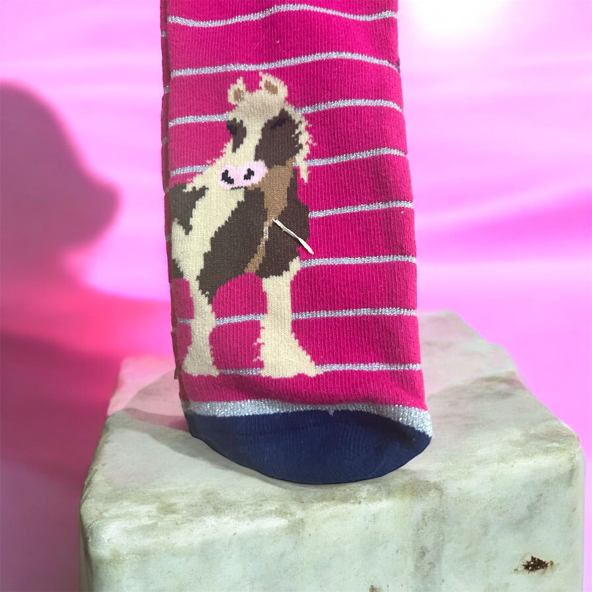 Sock with cow design on a pink and white striped background